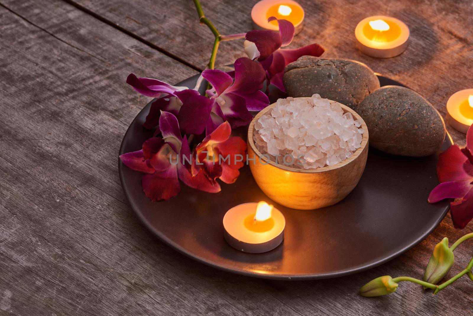 bath salt at bamboo bowl and orchids flowers on dark wood