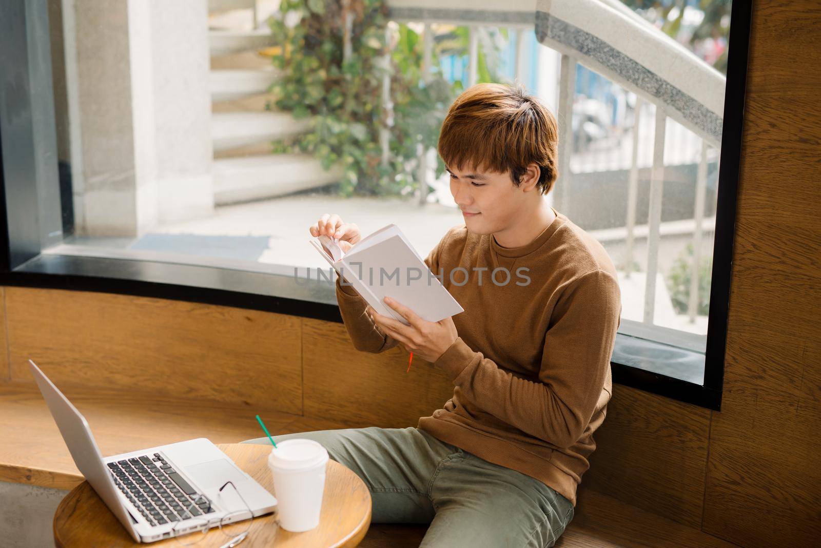 Businessman using laptop with tablet and pen on wooden table in coffee shop with a cup of coffee by makidotvn