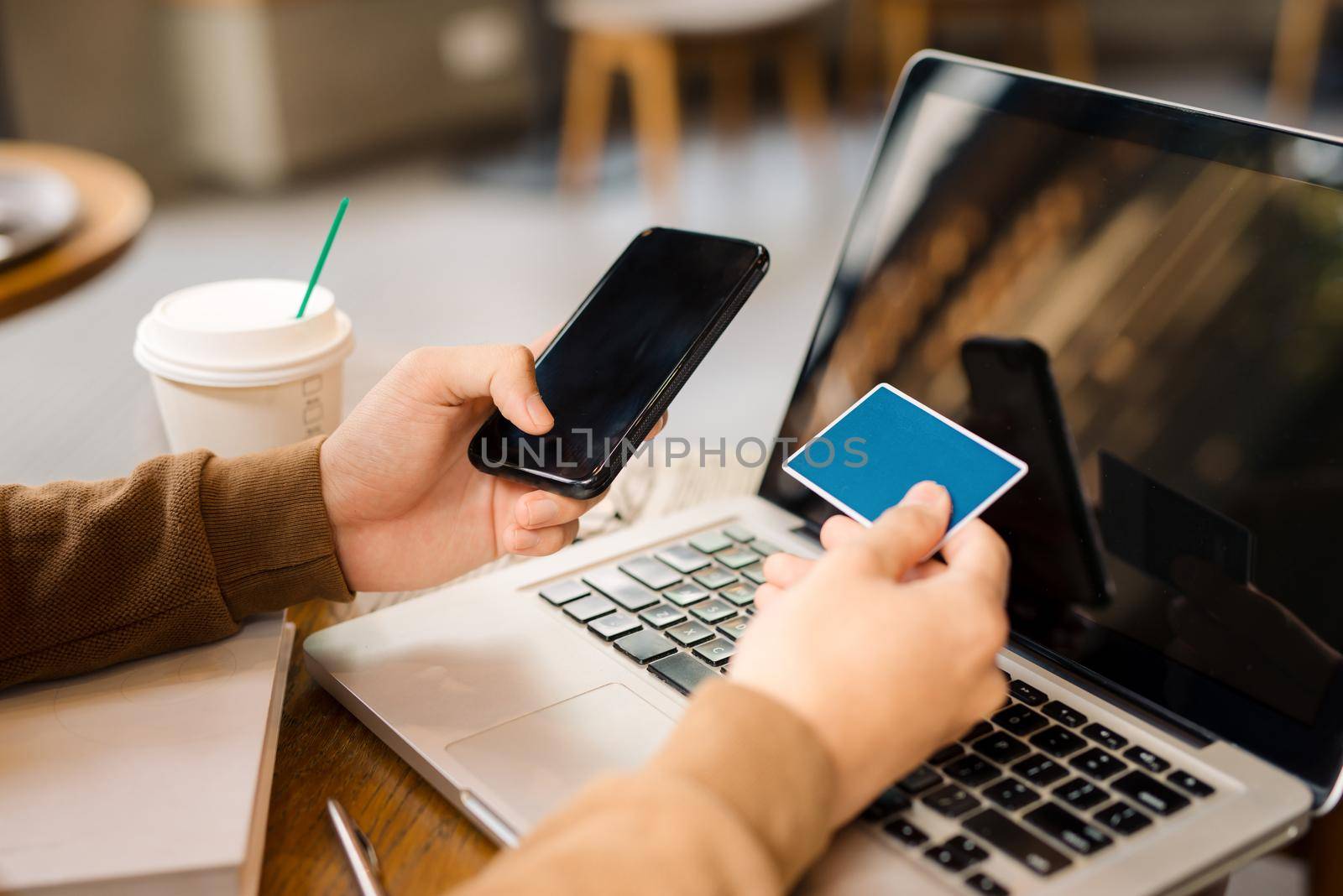 Online payment,"Woman's hands holding a credit card and using smart phone for online shopping in coffee shop