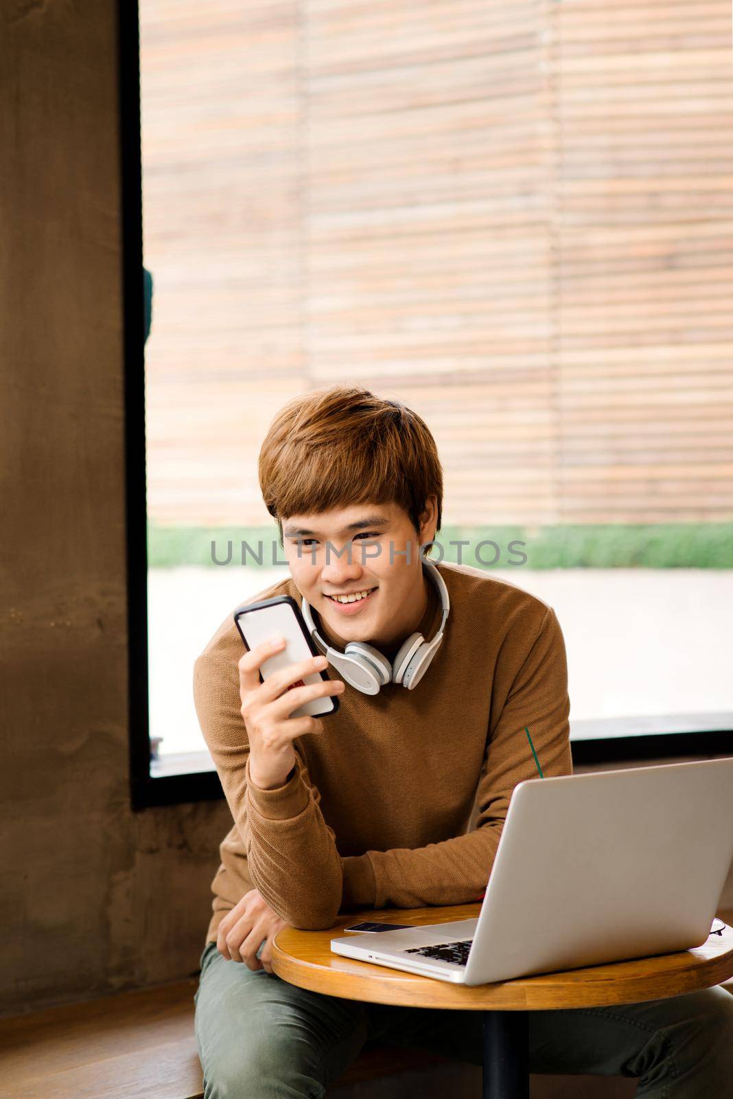 Handsome hipster man receive messages from friend texting answer while chatting through application on smartphone connected to free 5G wireless, male photographer using gadgets in cozy coffee shop by makidotvn