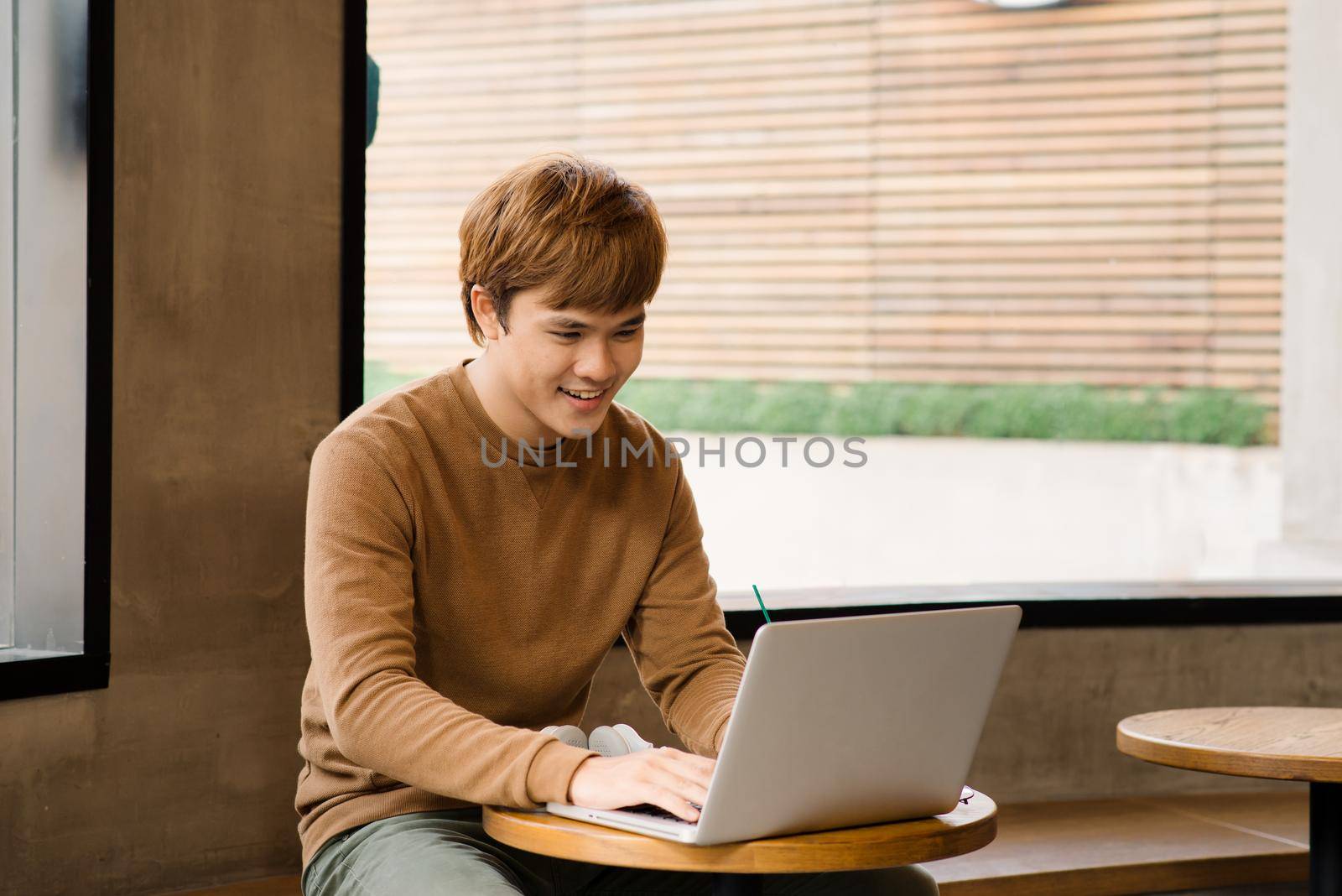 Male freelancer connecting to wireless via laptop computer, thoughtful businessman work on notebook while sitting at wooden table in modern coffee shop interior, student reading text or book in cafe by makidotvn