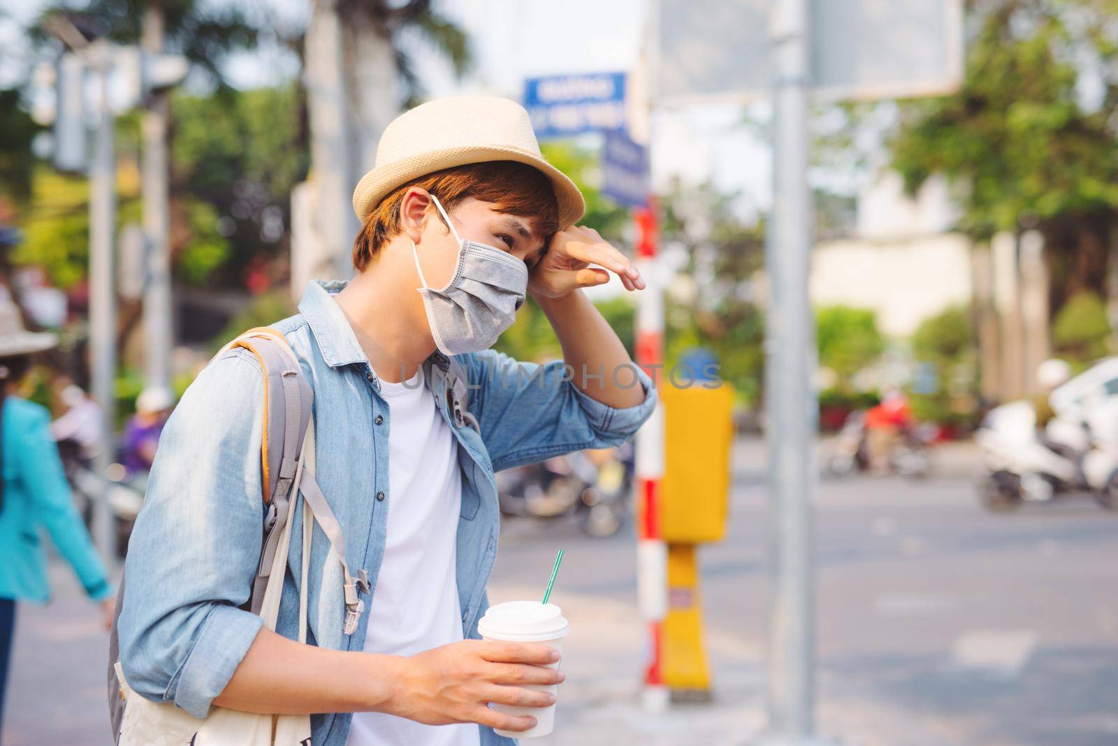 Young man in protective mask feeling bad on the street in the city with air pollution by makidotvn