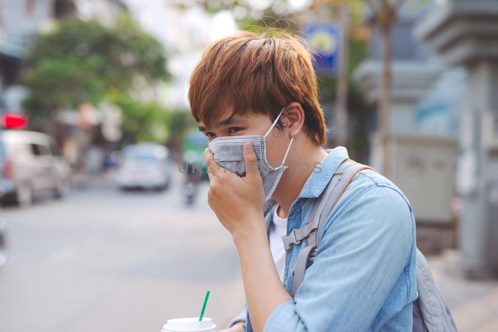 Asian man in the street wearing protective masks., Sick man with flu wearing mask and blowing nose into napkin as epidemic flu concept on the street.