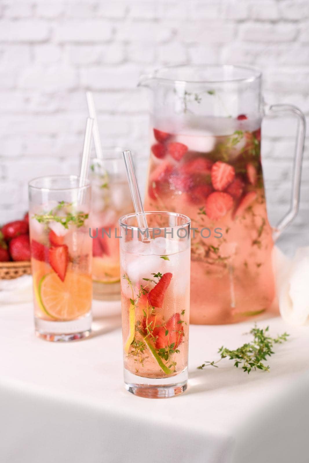 Strawberry summer cocktail or lemonade with thyme and lemon. Cold refreshing organic soft drink with ripe berries in a glass