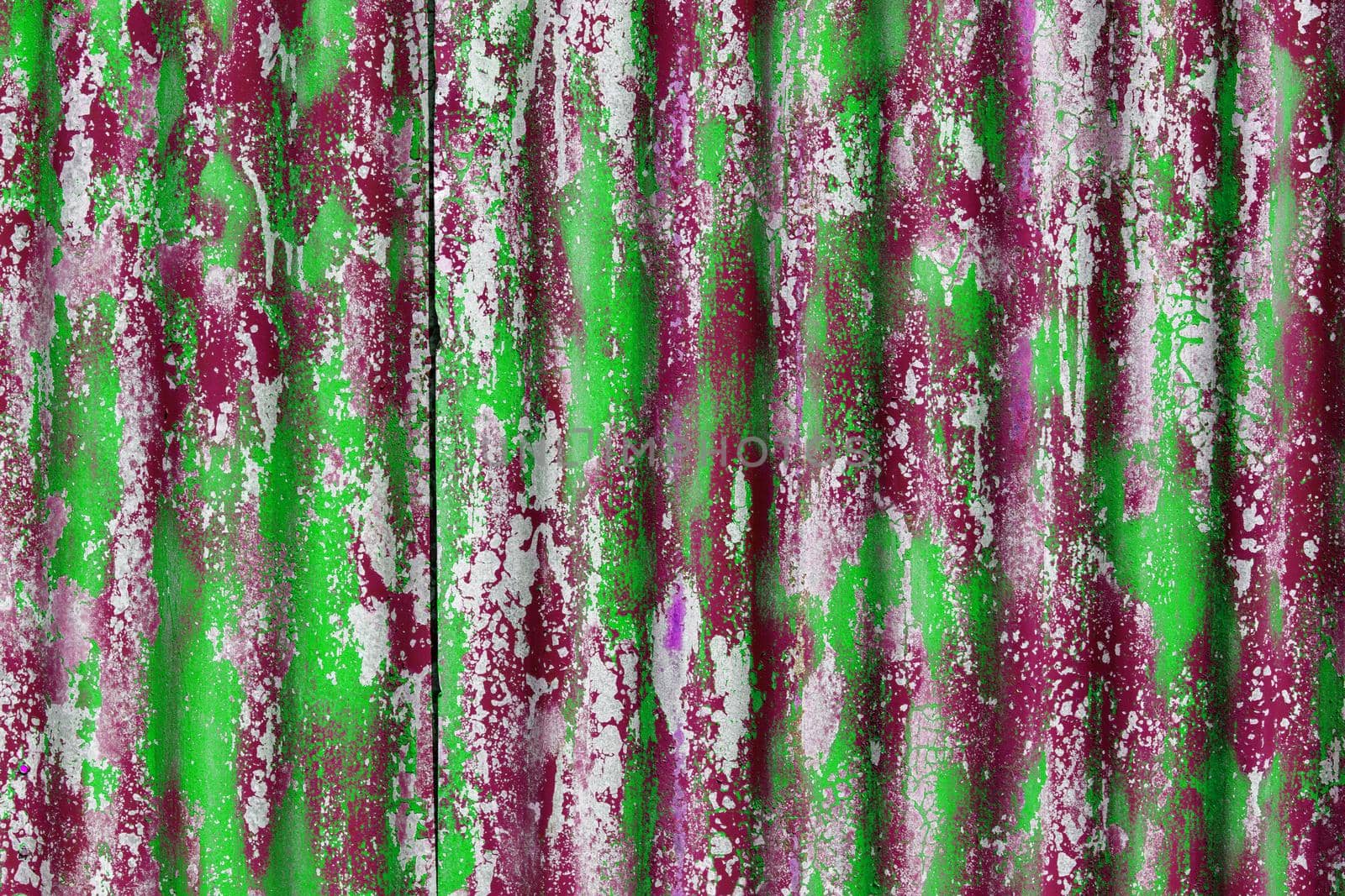 colorful motley peeled off paint layers on corrugated zinc coated steel sheet - full frame background and texture