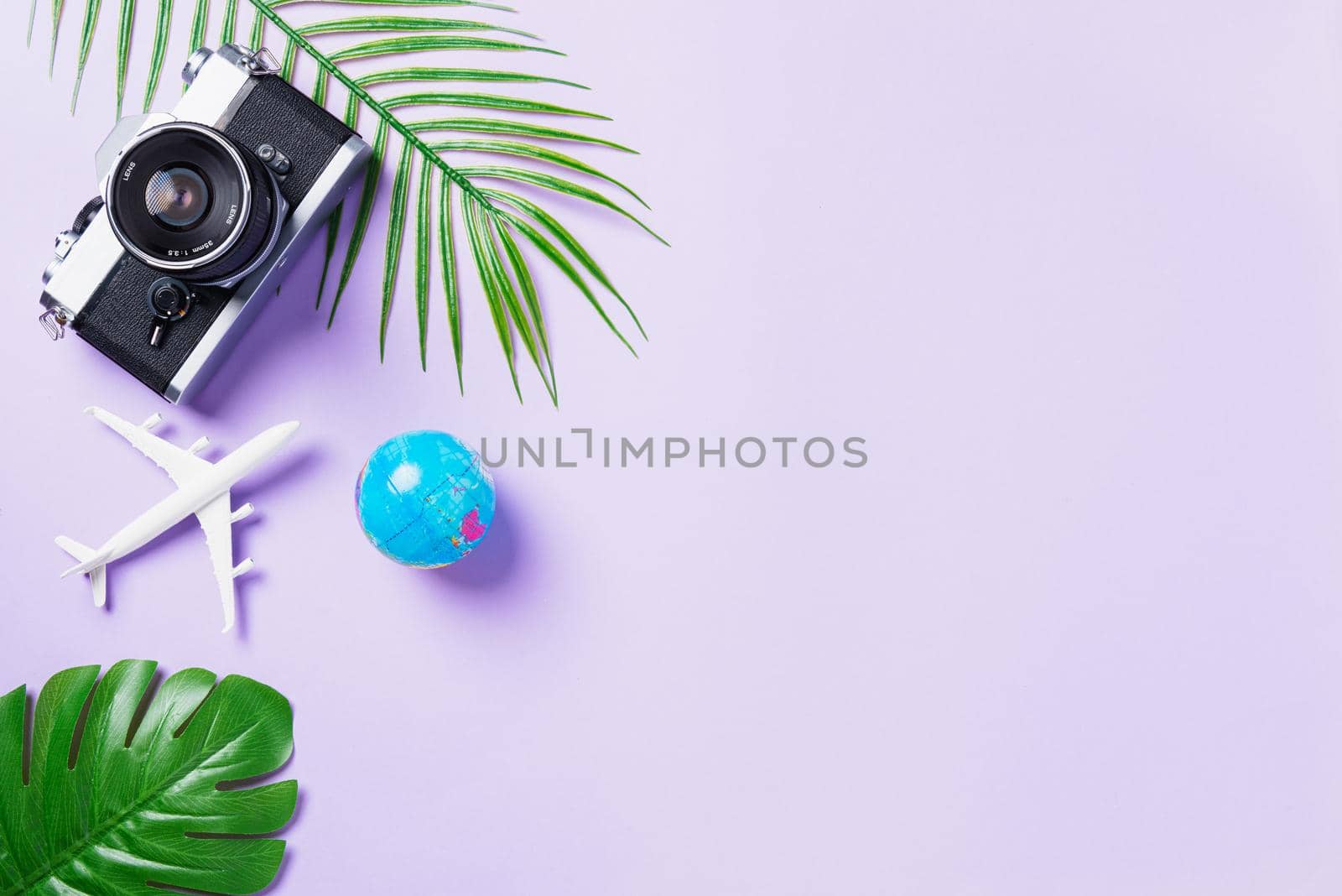 Top view flat lay mockup of retro camera films, airplane, passport, world and traveler accessories isolated on a purple background with copy space, Business trip, and vacation summer travel concept