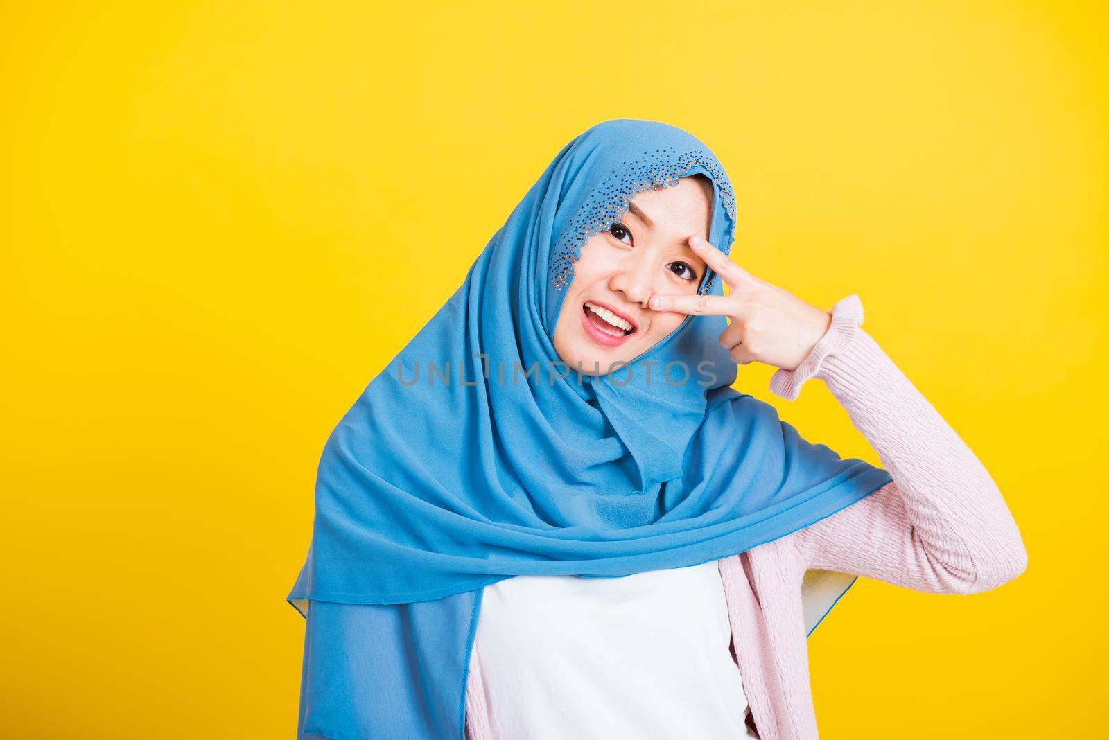 Asian Muslim Arab woman Islam wear hijab smile she showing gesture hand two finger V-sign symbol by Sorapop