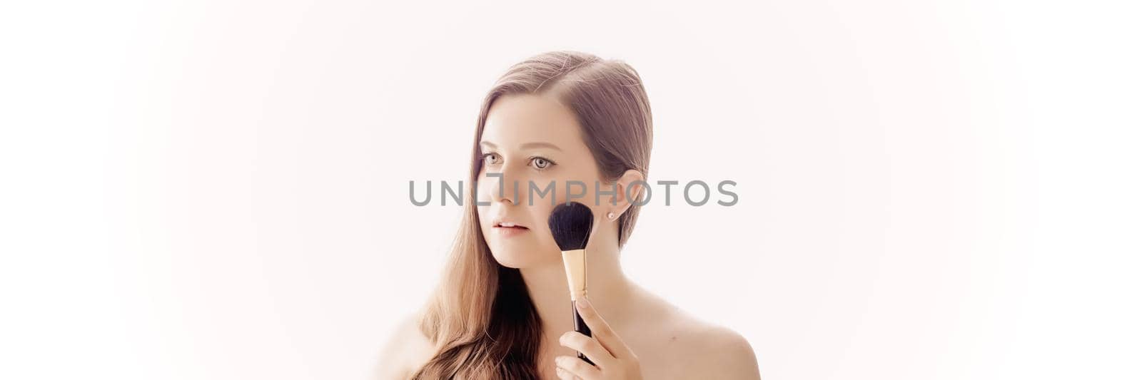 Beautiful woman with makeup brush, perfect skin and shiny hair as make-up, health and wellness concept. Face portrait of young female model for skincare cosmetics and luxury beauty ad design.