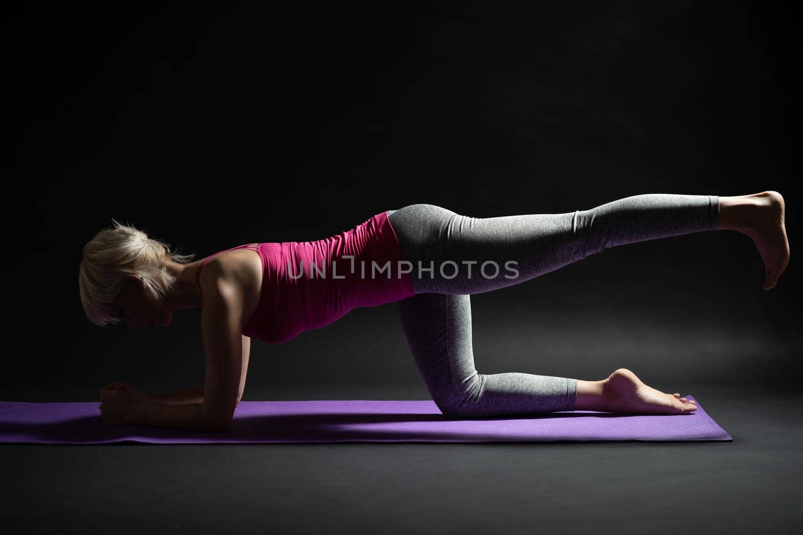 Woman exercising pilates. Kneeling back kick exercise.