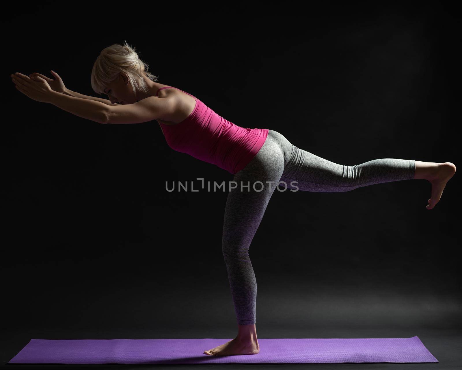 Woman exercising pilates. Variation of standing bird - dog exercise.