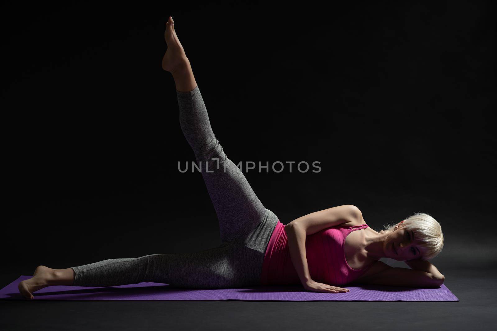Woman exercising pilates. Side lying leg raise exercise.