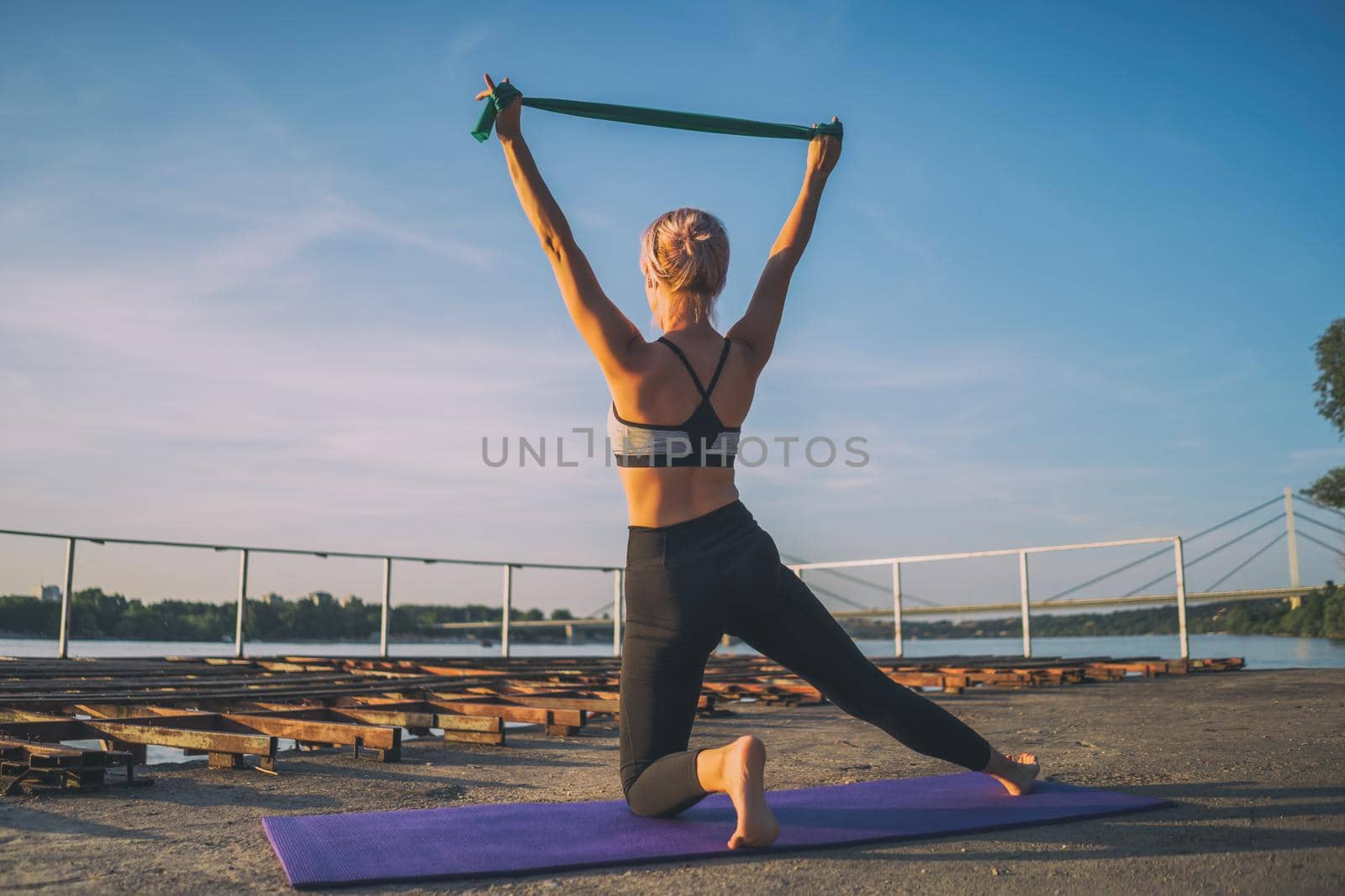 Woman exercising pilates with elastic band on sunny day.