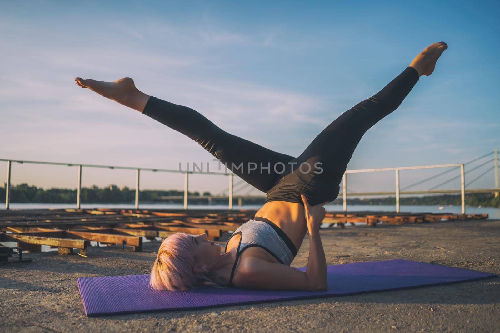 Woman exercising pilates on sunny day. Scissors exercise.