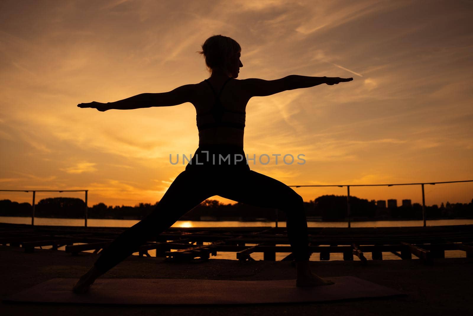 Woman practicing yoga in sunset. Virabhadrasana / Warrior 2 pose