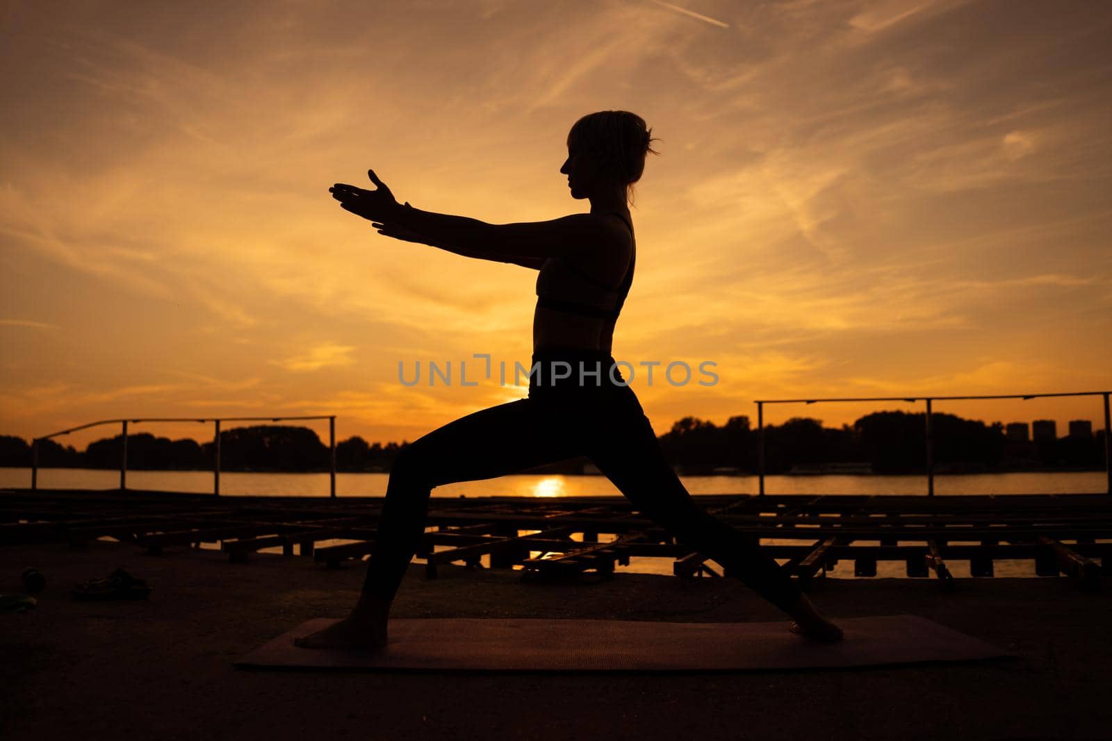 Woman practicing yoga in sunset. Virabhadrasana / Warrior pose