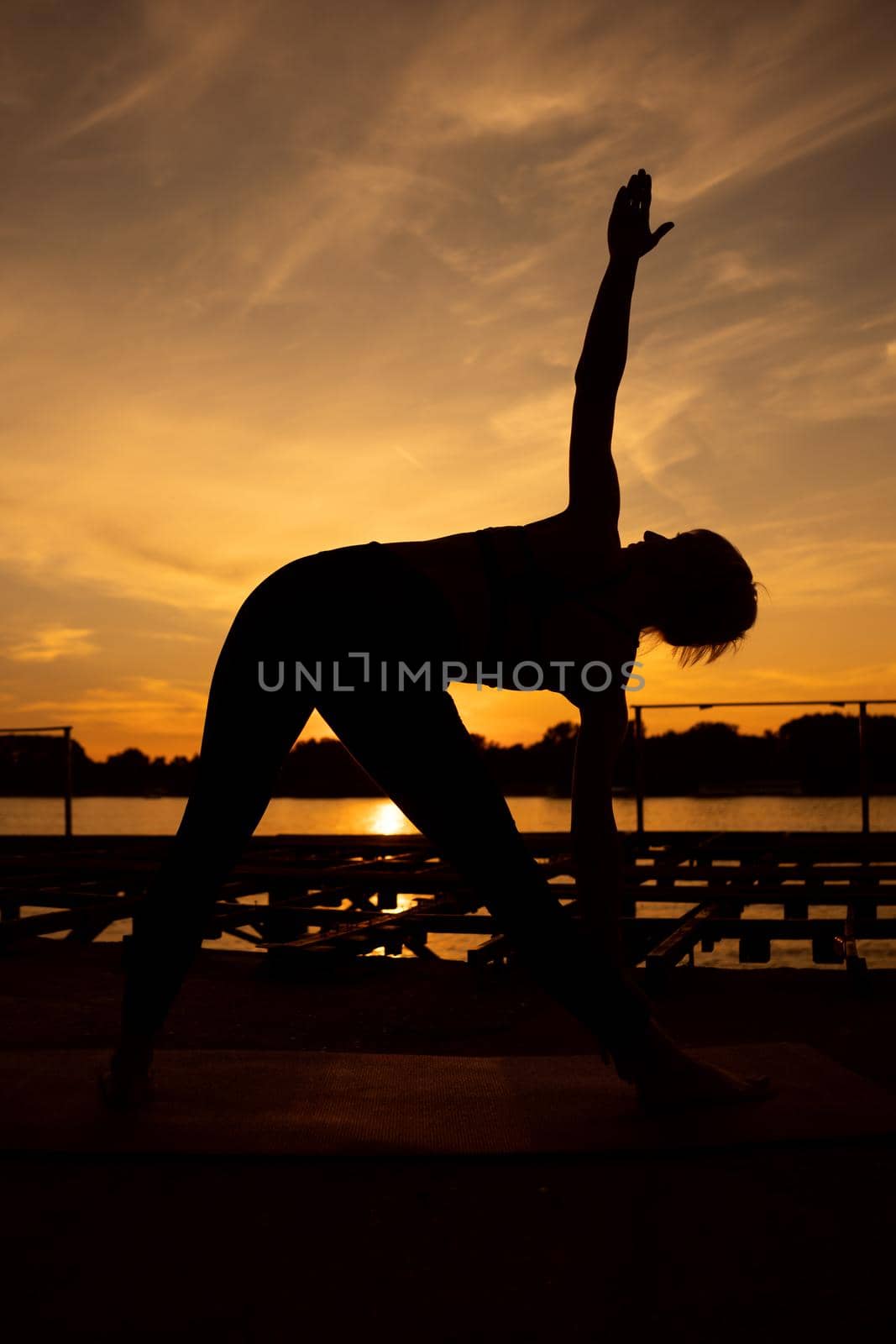 Woman practicing yoga in sunset. Trikonasana, Bikram triangle right