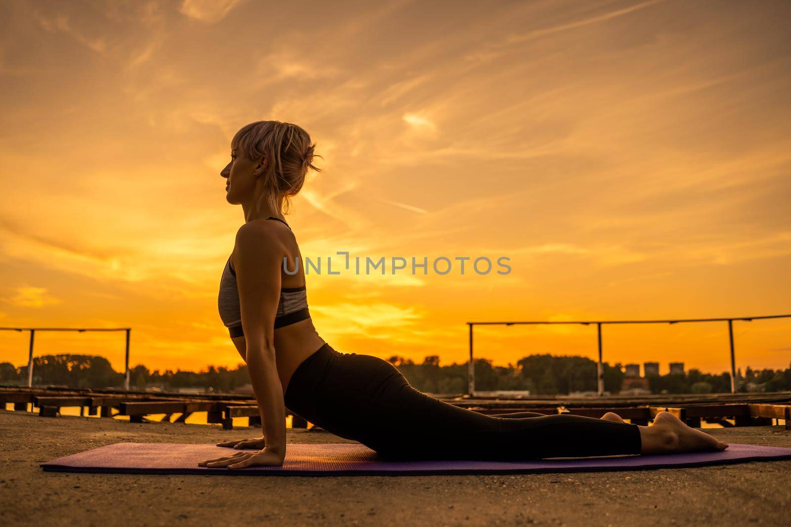 Woman practicing yoga in sunset. Bhujangasana/Cobra Pose