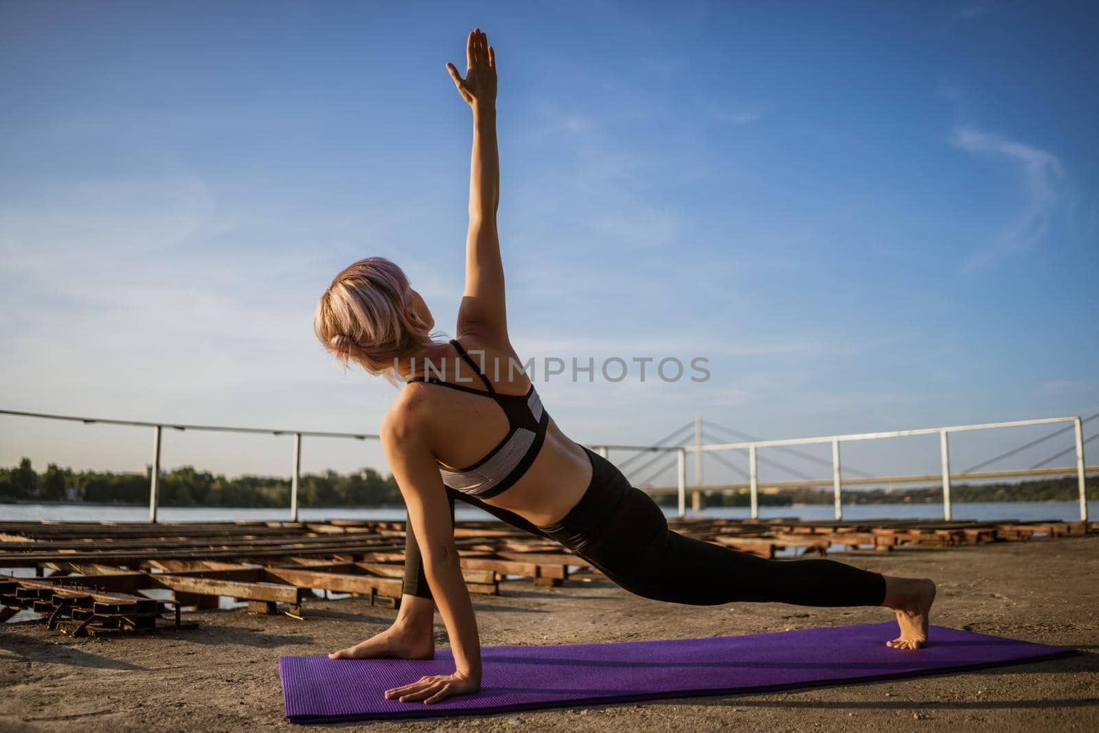 Woman practicing yoga on sunny day. Virabhadrasana, Rotated warrior pose.