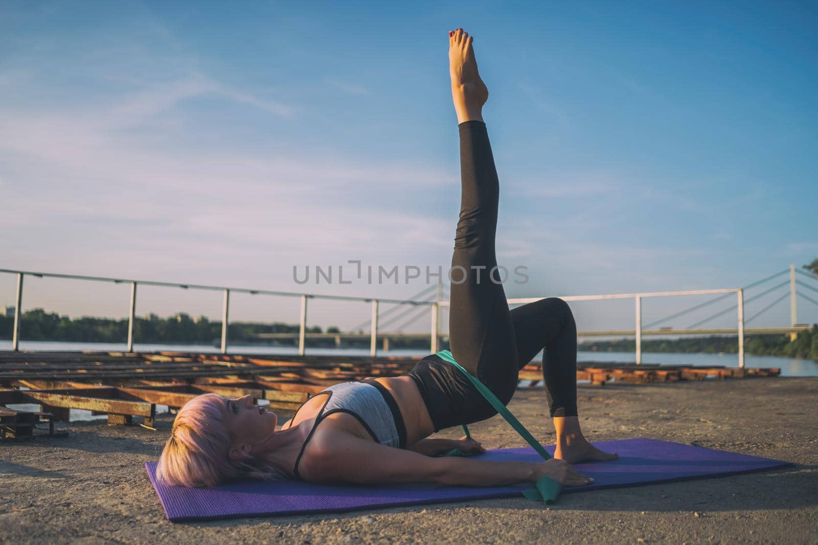 Woman exercising pilates with elastic band on sunny day.