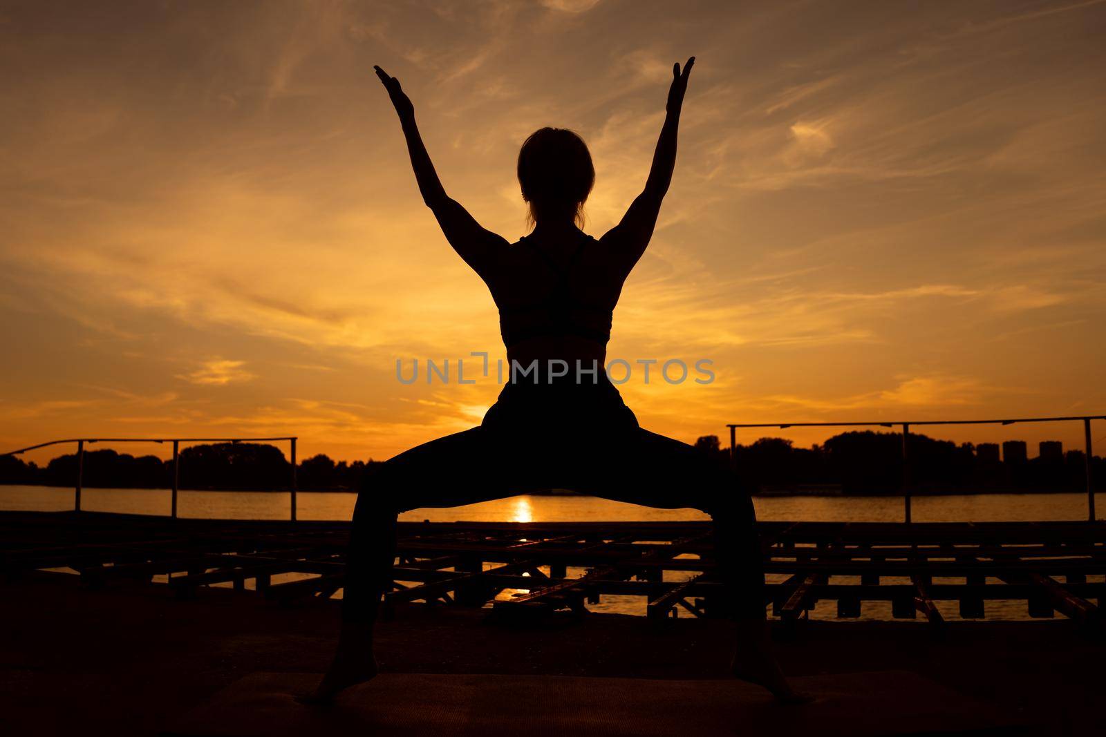 Woman practicing yoga in sunset. Utkatasana, Chair pose