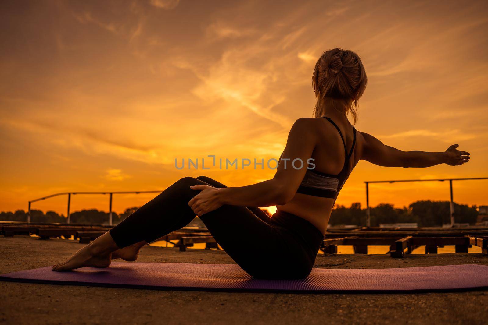 Woman exercising pilates in sunset.