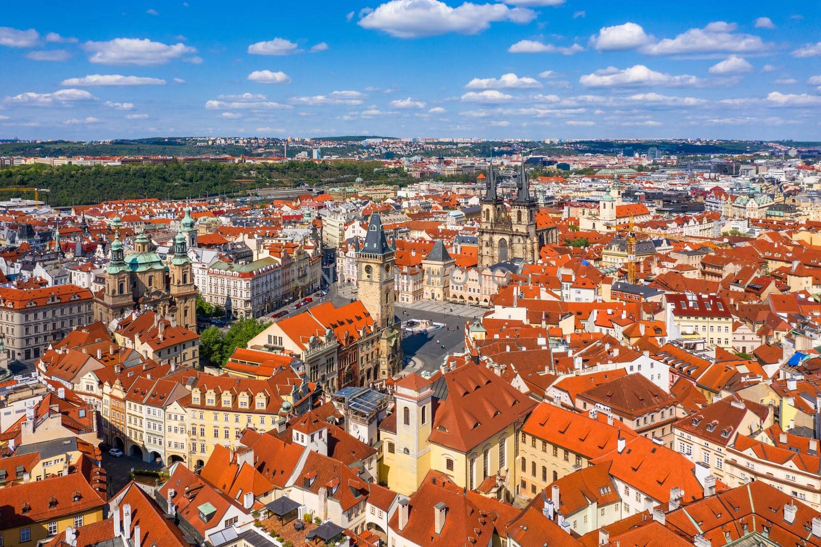 Prague beautiful panoramic sunny aerial drone view above Prague Old Town Square with Church of Our Lady before Tyn and Prague Astronomical Clock Tower. Drone flight over red roofs of Prague, Czechia.