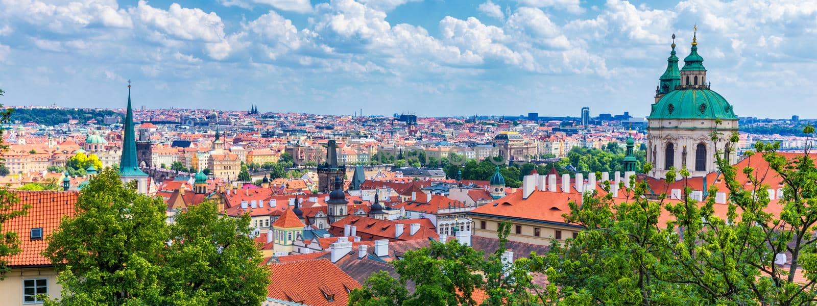 Prague red roofs and dozen spires of historical Old Town of Prague. Cityscape of Prague on a sunny day. Red rooftops, spires and the Charles Bridge and Vltava River in the background. Prague, Czechia.