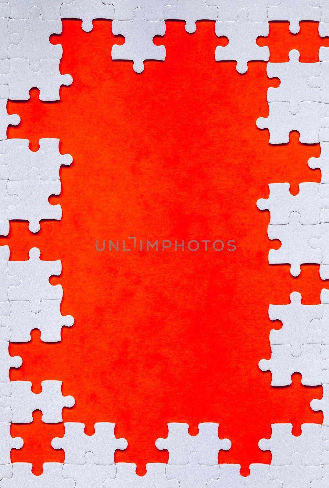 Framing in the form of a rectangle, made of a white jigsaw puzzle. Frame text and jigsaw puzzles. Frame made of jigsaw puzzle pieces on orange background.