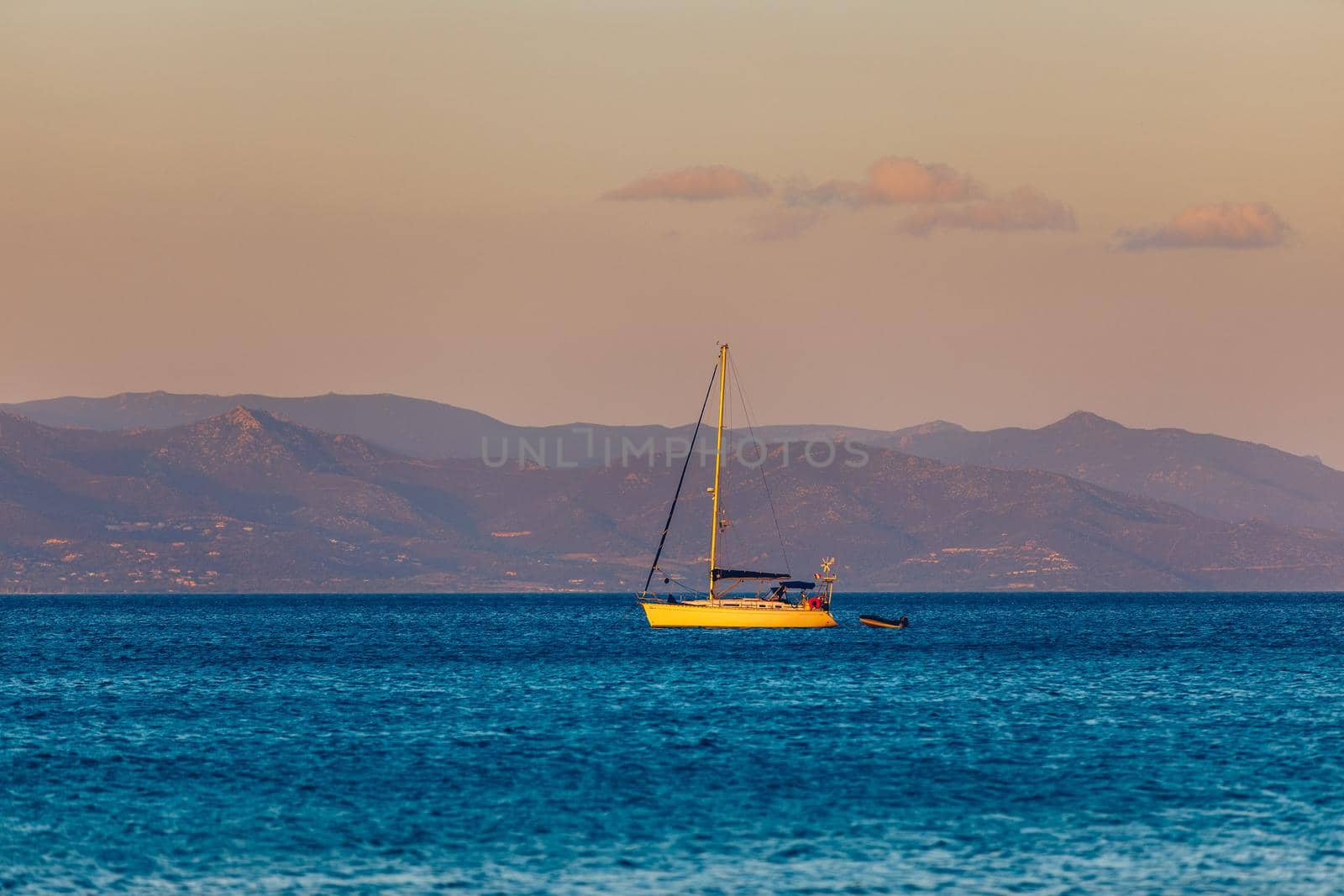 Yacht anchoring in crystal clear turquoise water in front of the tropical island, alternative lifestyle, living on a boat. Aerial view of yacht at anchor on turquoise water, showing luxury, wealth.
