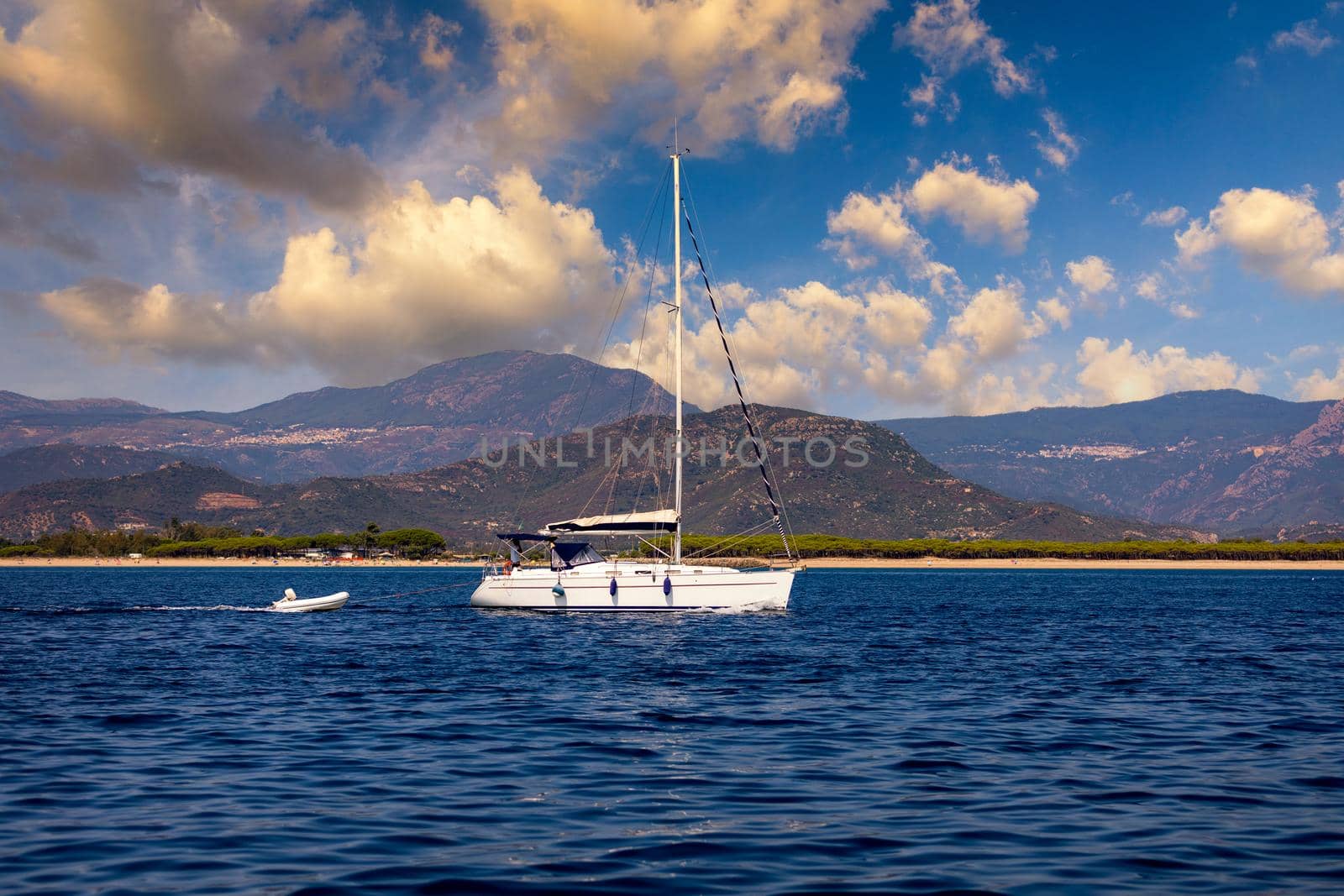 Yacht anchoring in crystal clear turquoise water in front of the tropical island, alternative lifestyle, living on a boat. Aerial view of yacht at anchor on turquoise water, showing luxury, wealth.