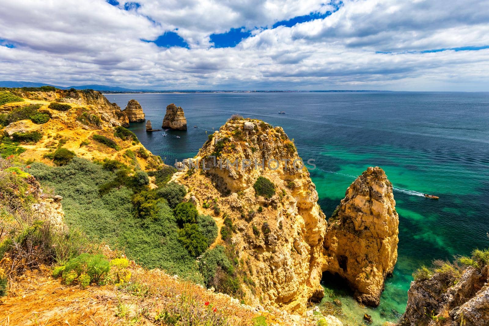 Panoramic view, Ponta da Piedade near Lagos in Algarve, Portugal. Cliff rocks and tourist boat on sea at Ponta da Piedade, Algarve region, Portugal. Ponta da Piedade, Algarve region, Portugal.