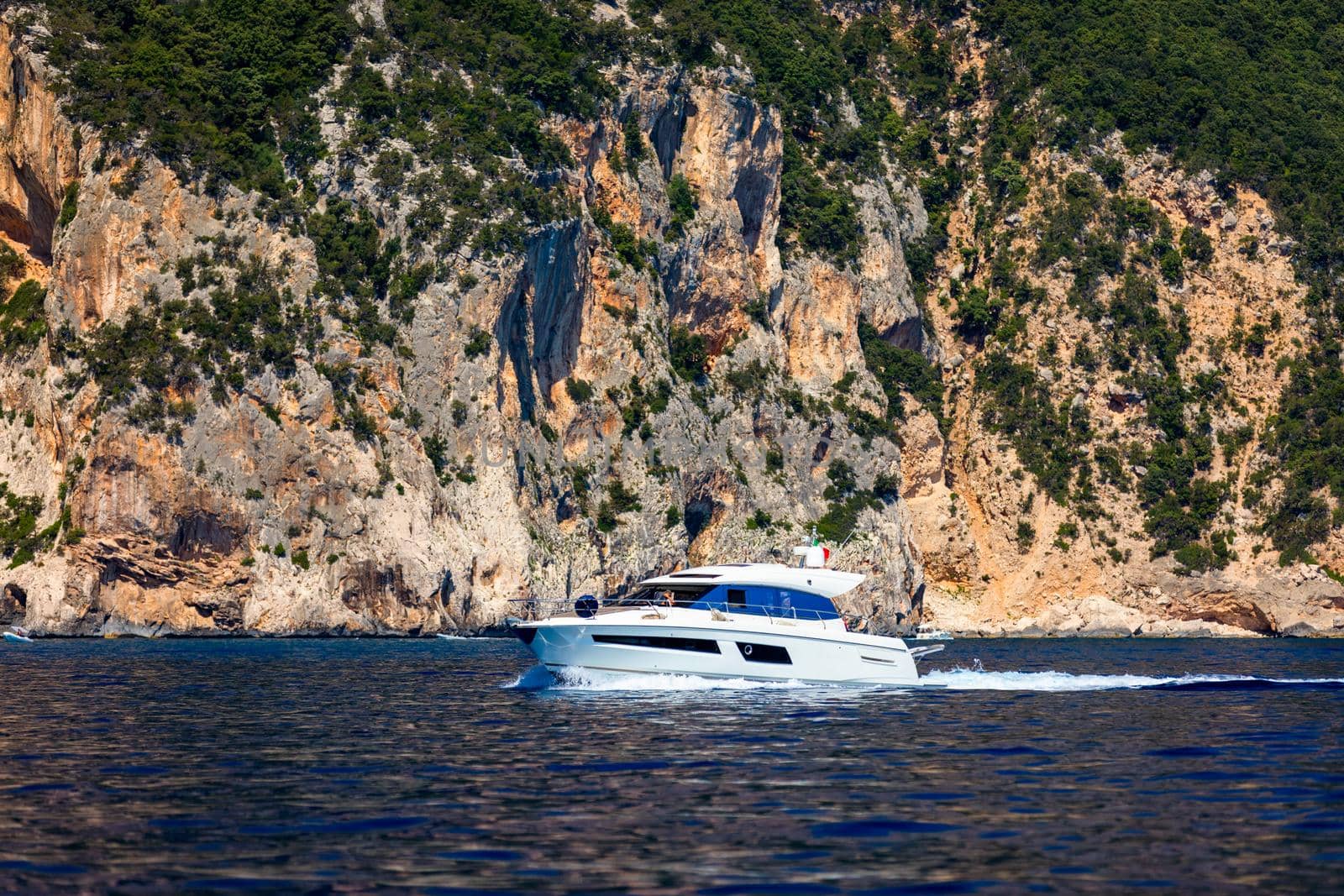 Yacht anchoring in crystal clear turquoise water in front of the tropical island, alternative lifestyle, living on a boat. Aerial view of yacht at anchor on turquoise water, showing luxury, wealth.