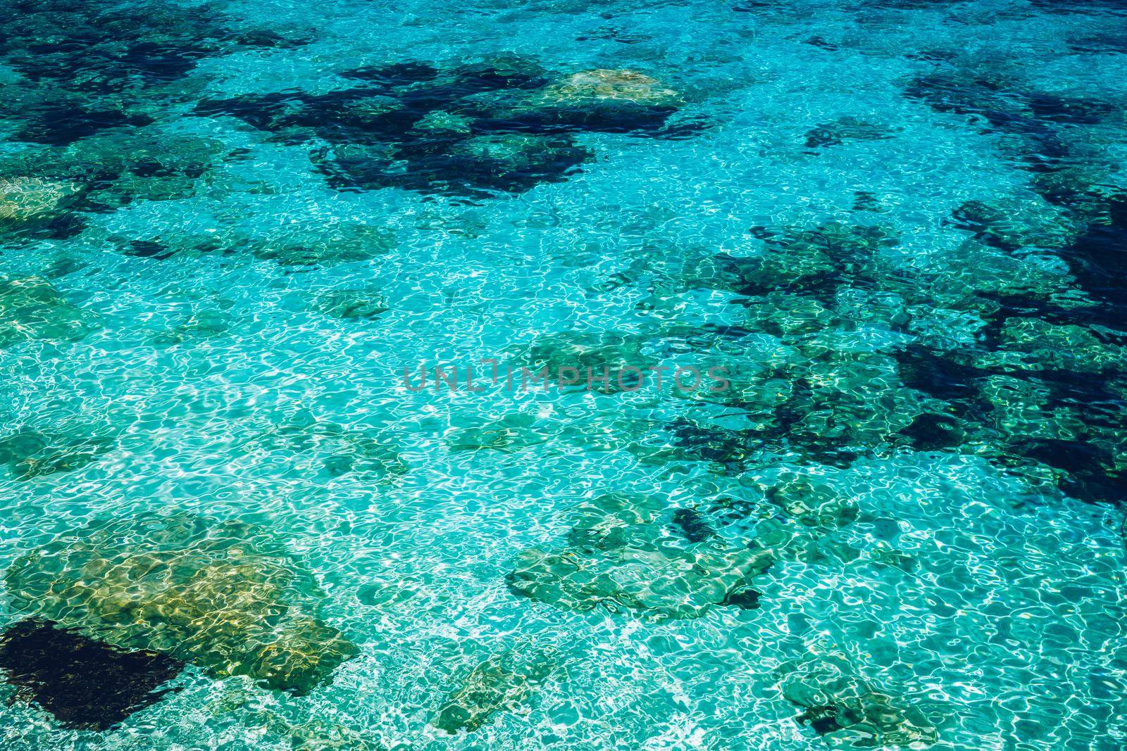 Water surface with bright sun light reflections, sea water background. Background of transparent sea water. Blue ripped sea water background.