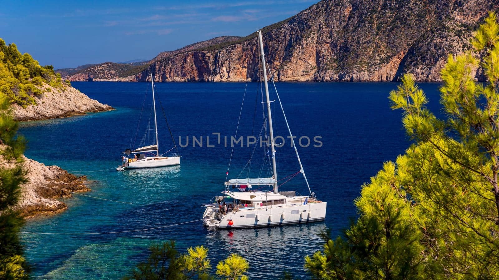 Aerial view of anchored sailing yacht in emerald sea. Aerial view of a boat. Outdoor water sports, yachting. Aerial view of anchoring yacht in open water. Ocean and sea travel and transportation