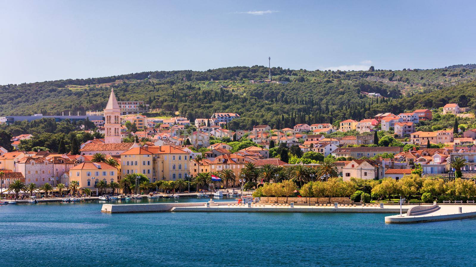 Supetar city in Brac island, Croatia. View from the sea. Picturesque scenic view on Supetar on Brac island, Croatia. Panoramic view on harbor of town Supetar from the side of sea. Brac, Croatia.