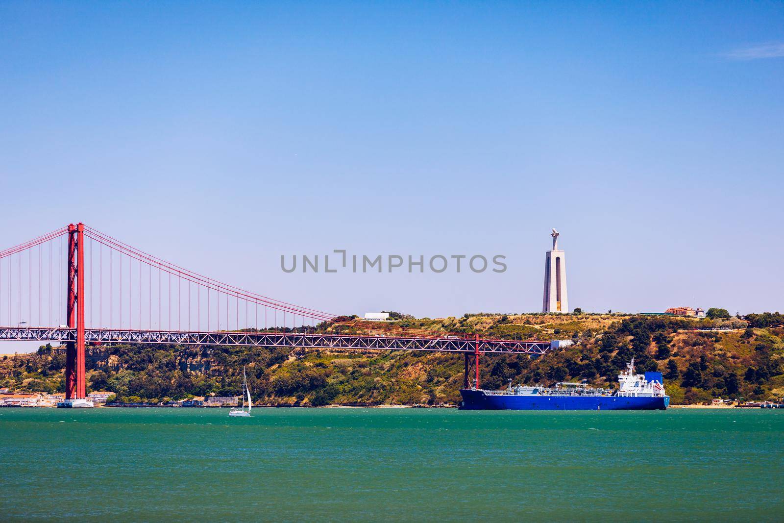 The 25 April bridge (Ponte 25 de Abril) is a steel suspension bridge located in Lisbon, Portugal, crossing the Targus river. Cristo Rei or Christ the King in the background. Lisbon. Portugal.