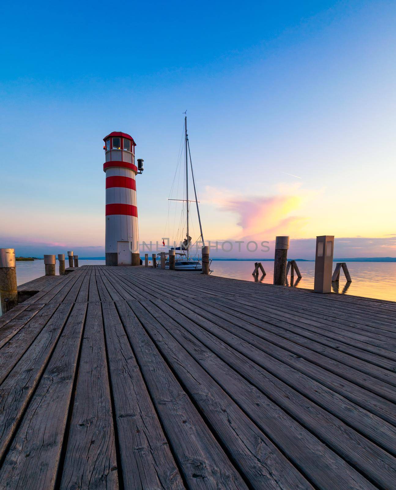 Lighthouse at Lake Neusiedl, Podersdorf am See, Burgenland, Austria. Lighthouse at sunset in Austria. Wooden pier with lighthouse in Podersdorf on lake Neusiedl in Austria.