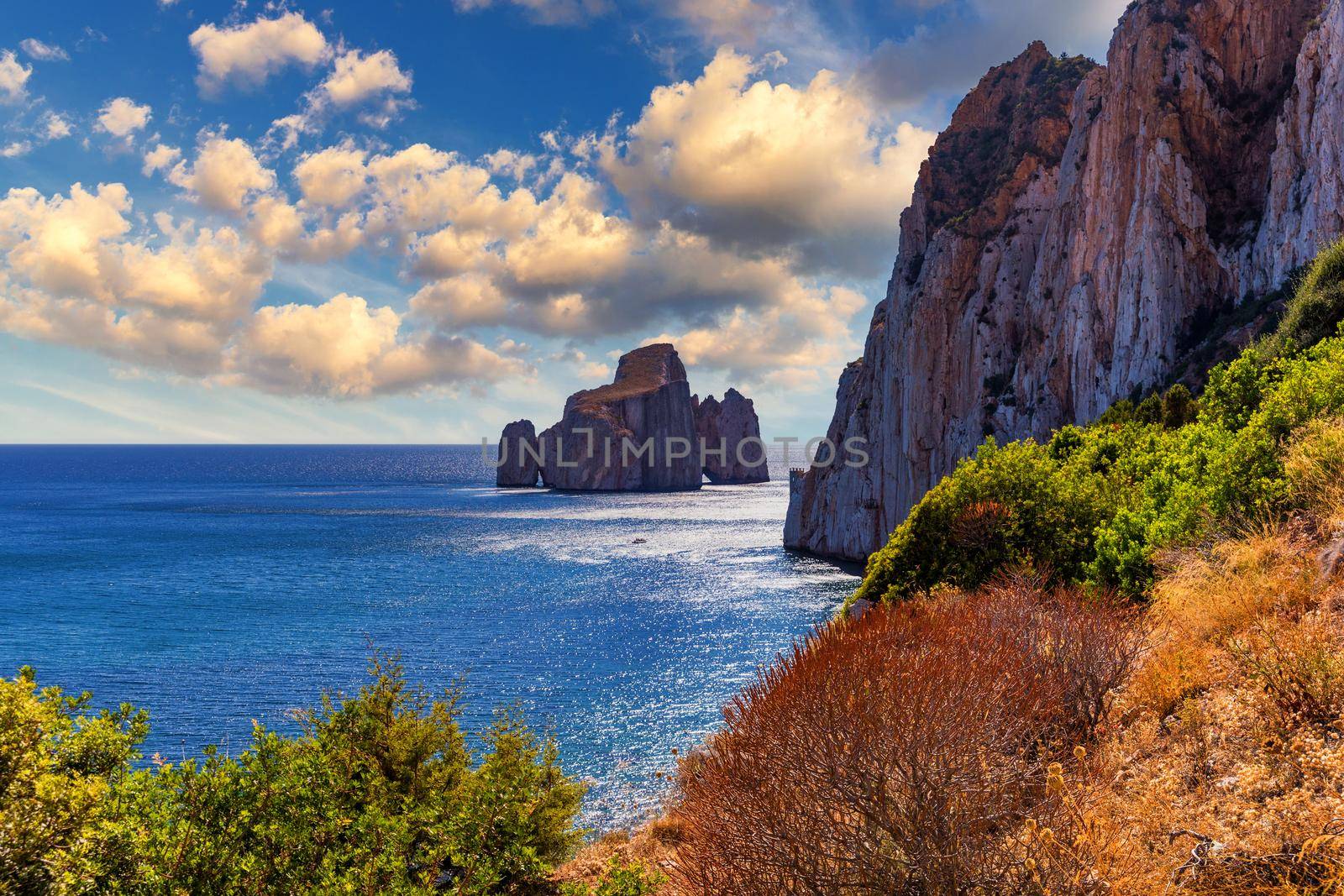 High cliffs of Mediterranean coast, "Pan di Zucchero" stack rock in Masua, west coast of Sardinia, Italy. Concali Su Terrainu with Porto Corallo on background. Sardinia island, Italy, Europe.