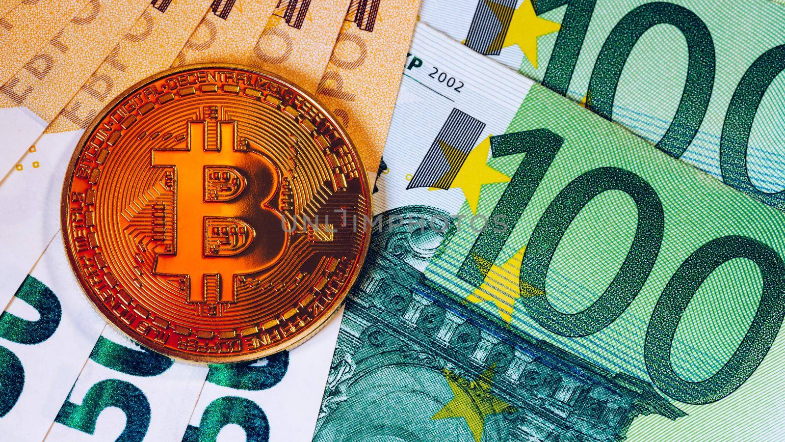 Golden bitcoin over Euro money. Bitcoin cryptocurrency. Crypto currency concept. Bitcoin with euro bills. Bitcoins stacked on euro banknotes.