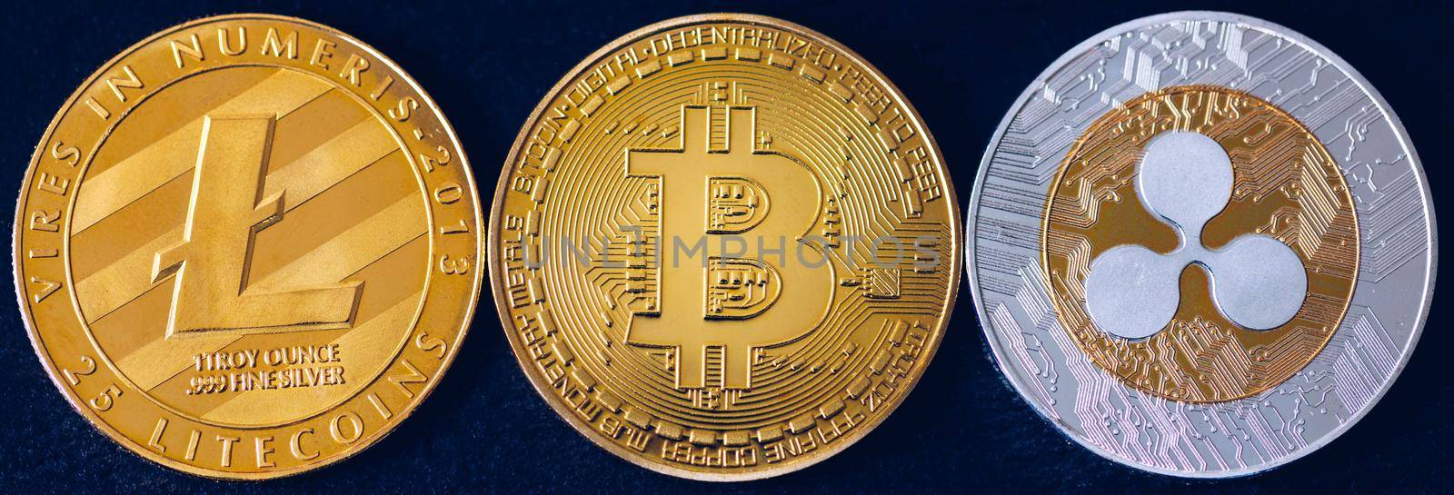 Bitcoin, litecoin and ripple coins currency finance money on graph chart background. Bitcoin as most important cryptocurrency concept. Stack of cryptocurrencies with a golden bitcoin in the middle.