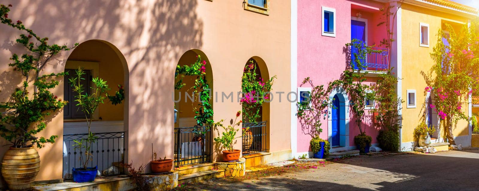 Traditional street with greek houses with flowers in Assos, Kefalonia island. Traditional colorful greek houses in Assos village. Blooming fuchsia plant flowers. Kefalonia island, Greece
