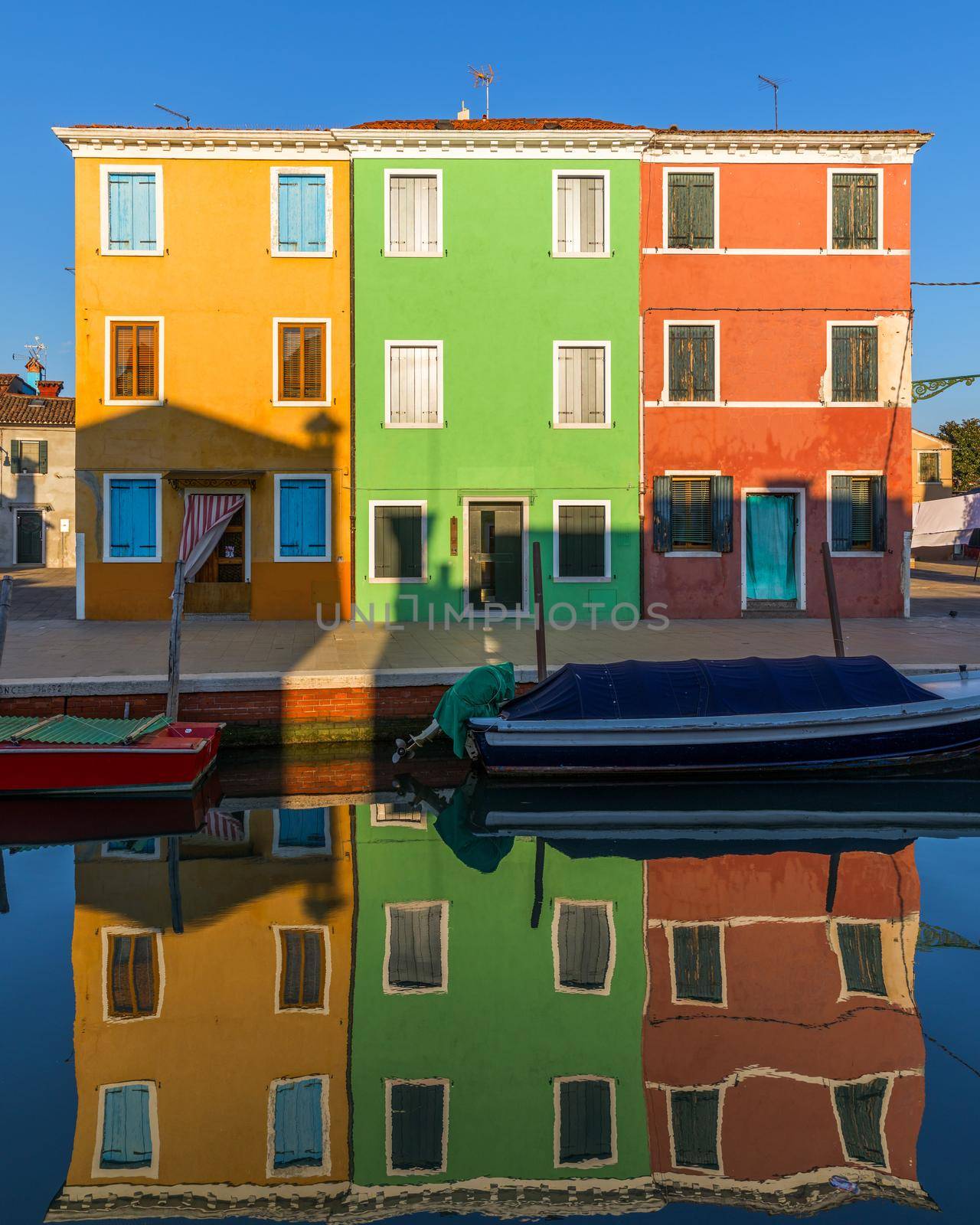Street with colorful buildings in Burano island, Venice, Italy. Architecture and landmarks of Burano, Venice postcard. Scenic canal and colorful architecture in Burano island near Venice, Italy