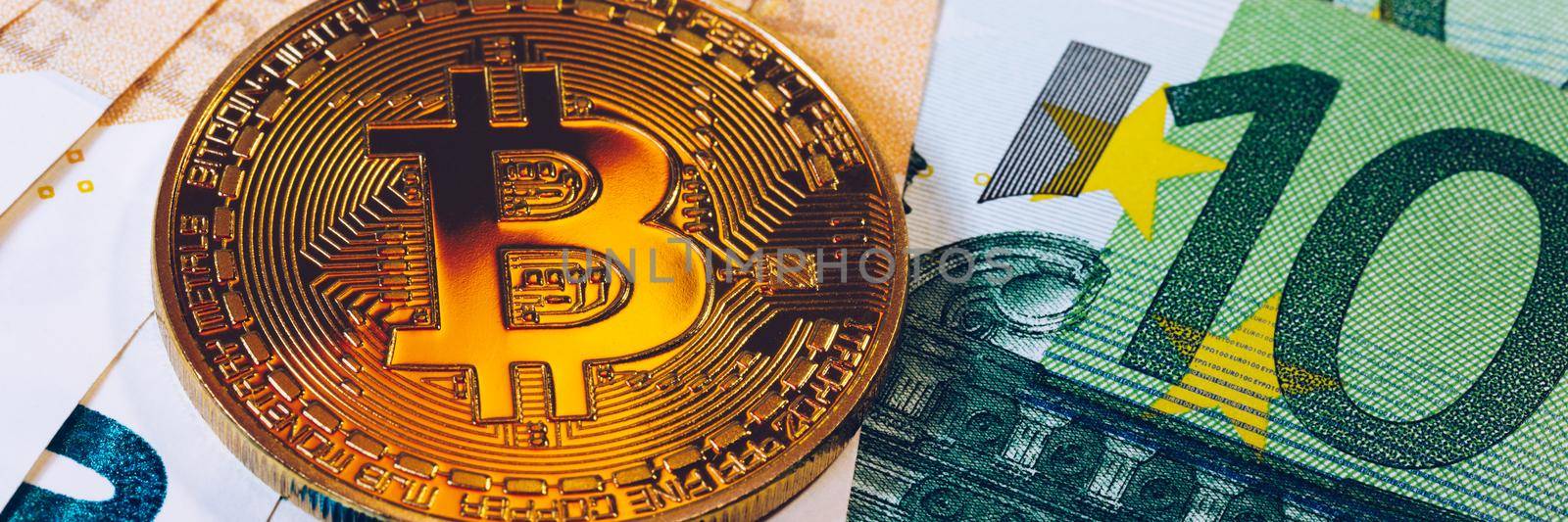 Golden bitcoin over Euro money. Bitcoin cryptocurrency. Crypto currency concept. Bitcoin with euro bills. Bitcoins stacked on euro banknotes.