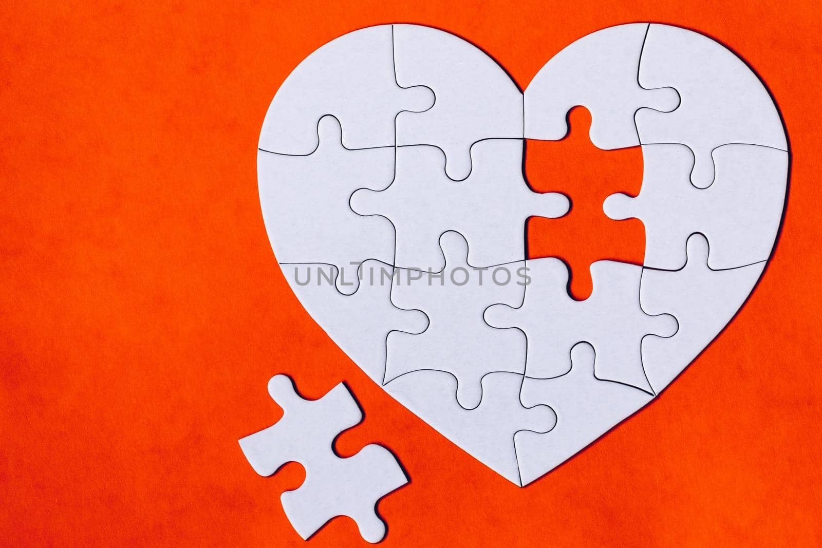 Heart-shaped jigsaw puzzle on color background. Puzzle heart on wooden background. A missing piece of the heart puzzle. Heart shape jigsaw puzzle. Puzzles in the shape of a heart. 