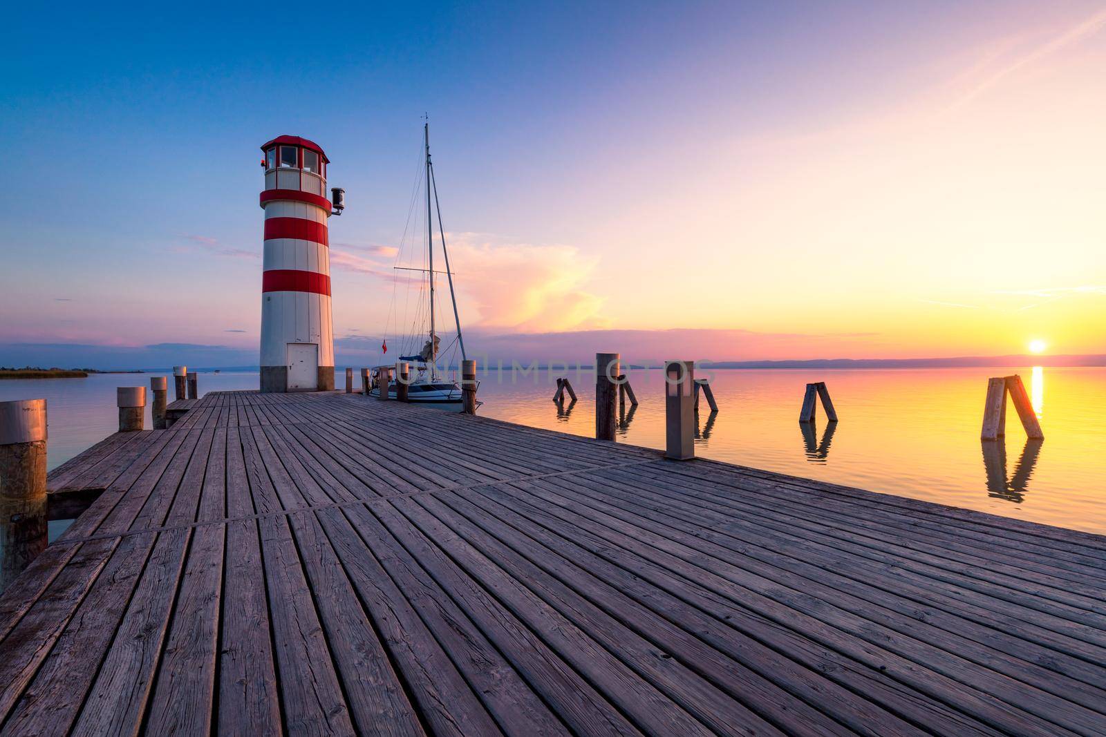 Lighthouse at Lake Neusiedl, Podersdorf am See, Burgenland, Austria. Lighthouse at sunset in Austria. Wooden pier with lighthouse in Podersdorf on lake Neusiedl in Austria.