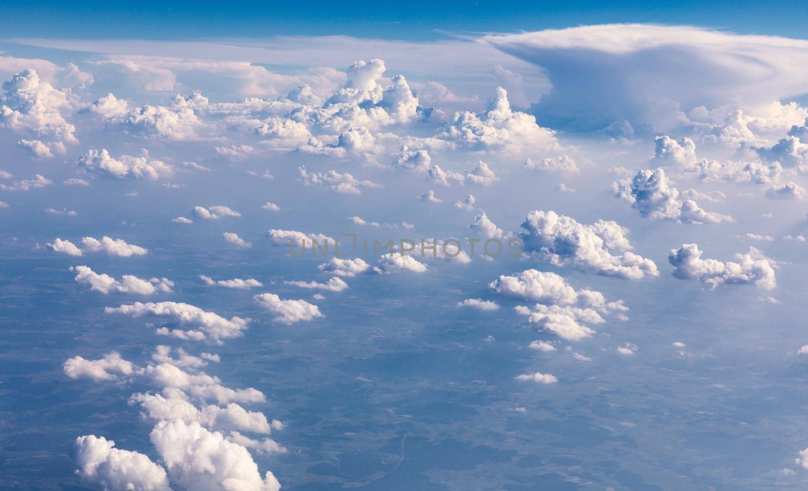 Amazing clouds and the sky as seen through the window of an aircraft. Clouds, sun, sky as seen through window of an aircraft. Bright blue sky with clouds and sunlight seen through an airplane window.
