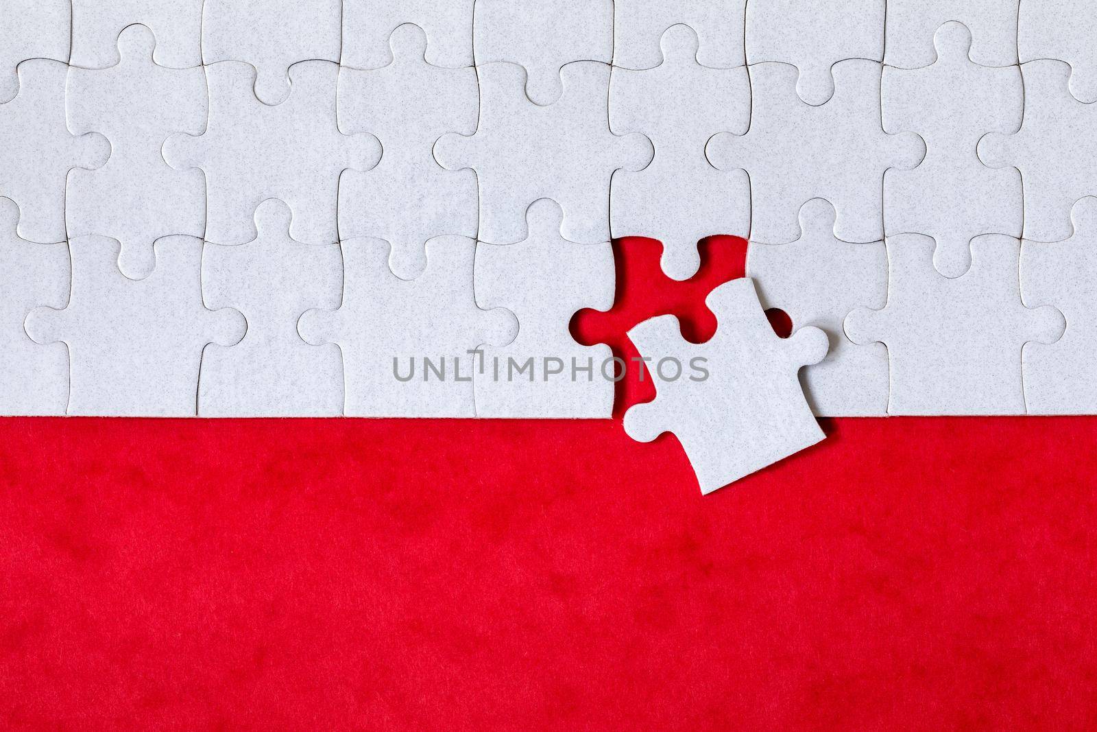 White jigsaw puzzle. White puzzle pieces on color background. Unfinished white jigsaw puzzle pieces on color background. 