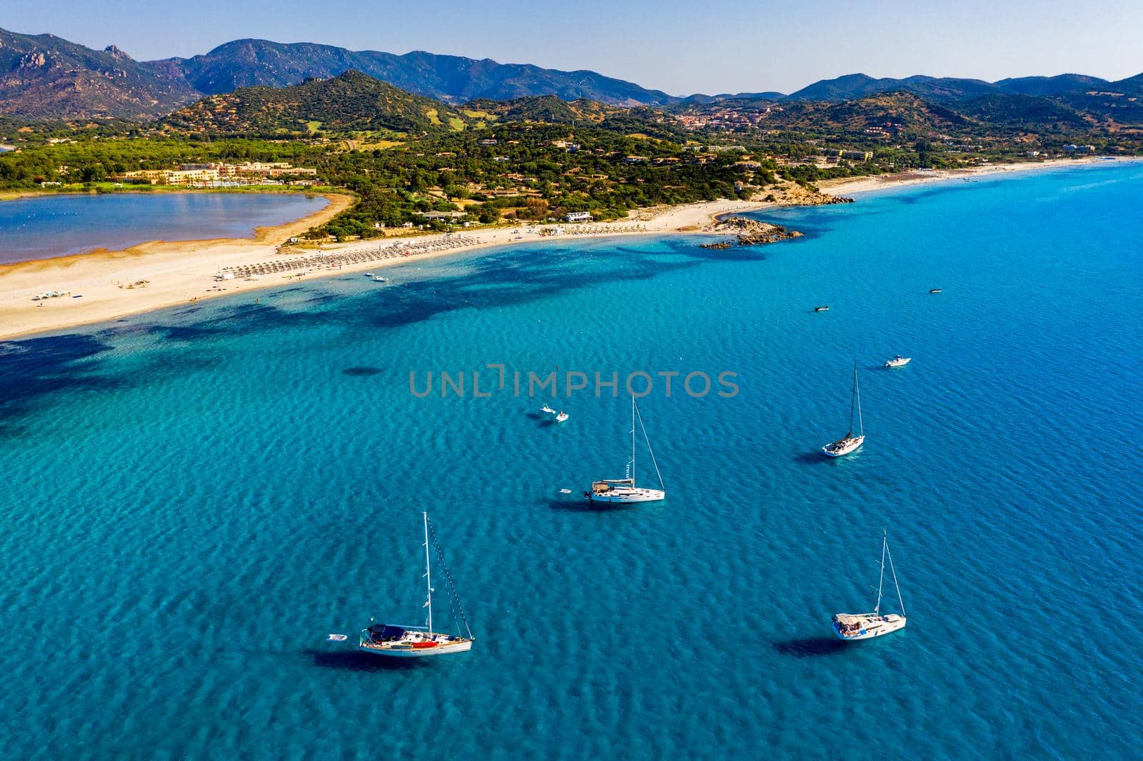 Aerial view of anchored sailing yacht in emerald sea. Aerial view of a boat. Outdoor water sports, yachting. Aerial view of anchoring yacht in open water. Ocean and sea travel and transportation