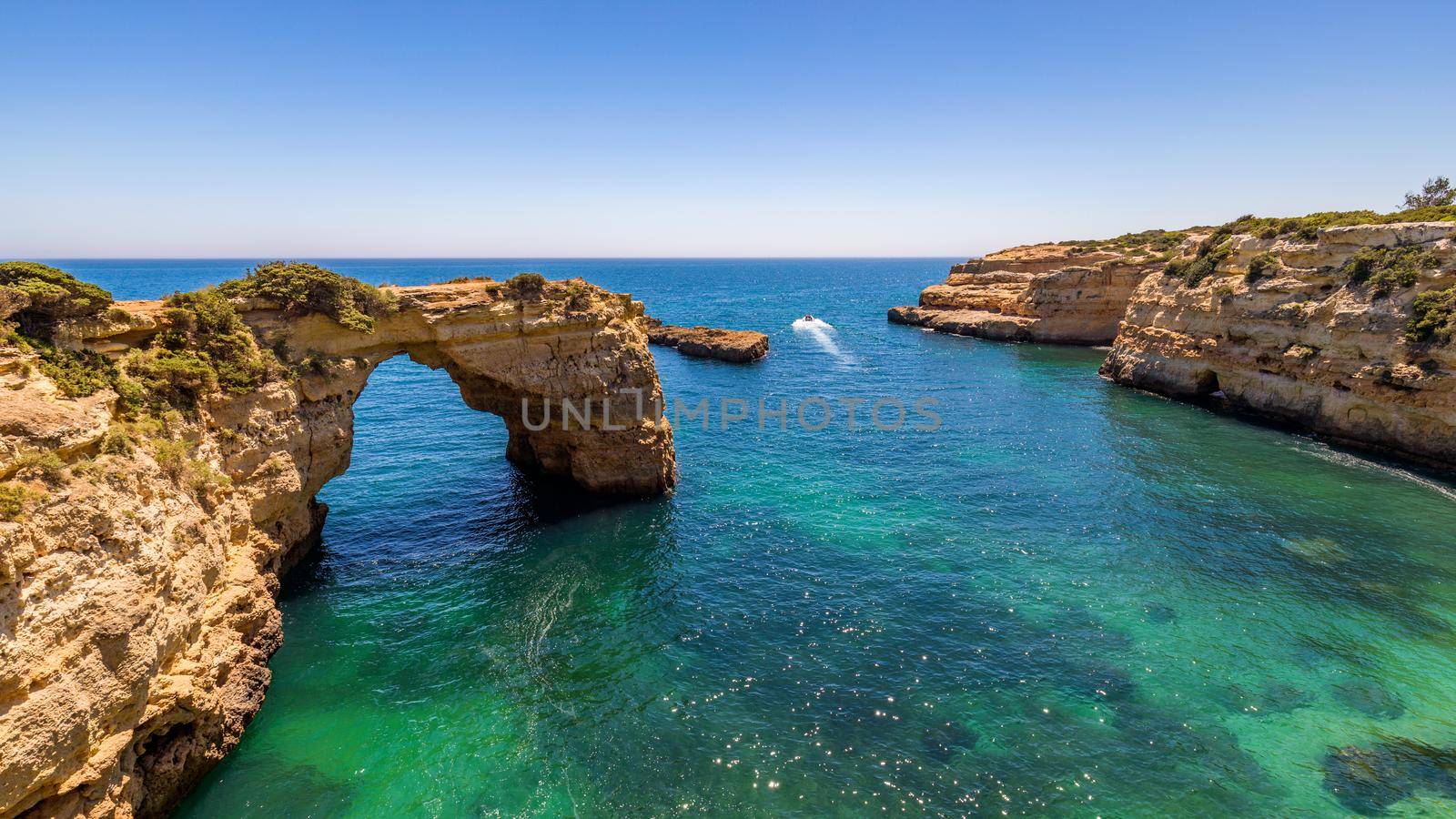 Natural arch above ocean, Arco de Albandeira, Algarve, Portugal. Stone arch at Praia de Albandeira, Lagoa, Algarve, Portugal. View of the natural arch Arco da Albandeira in the Algarve, Portugal. 