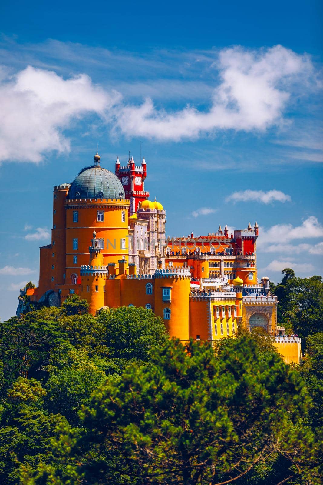 Famous historic Pena palace part of cultural site of Sintra against sunset sky in Portugal. Panoramic View Of Pena Palace, Sintra, Portugal. Pena National Palace at sunset, Sintra, Portugal. 